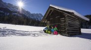 Familie vor Heustadel im Schnee