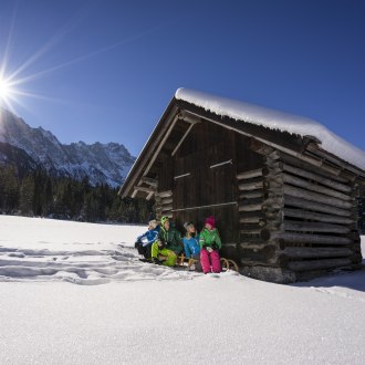 Familie vor Heustadel im Schnee